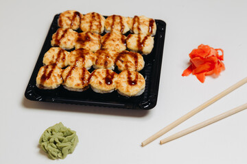 Set of baked sushi rolls with wasabi and ginger on a white background