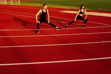  Young men and women doing stretching before running at the stadium.