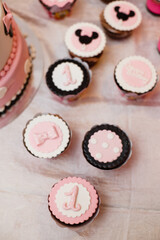 A festive table setting with a lot of sweets: muffins, cupcakesetc. for celebrating of first Birthday of little girl. Candy bar. Birthday party