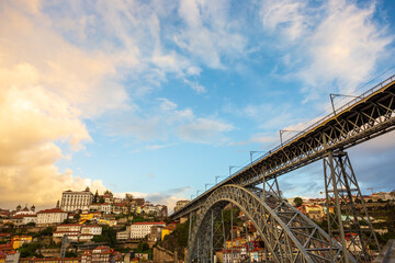 Morning in Porto Portugal: Ribeira district featuring Ponte Luis I bridge and Episcopal palace on the top of the hill, under magnificent orange glowing clouds in a blue sky. Copy space.