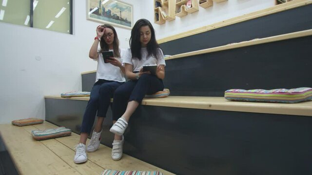 Two friends are reading books in modern classroom