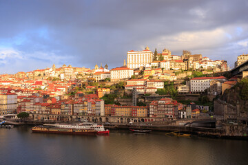 Fototapeta na wymiar Morning in Porto Portugal: Dark clouds in the sky above Douro river and Ribeira district, featuring sunlit Episcopal palace on the top of the hill.