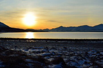 golden sunrise sky over snowy mountain, fjord and field