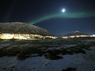 aurora borealis over snow capped mountain and full moon