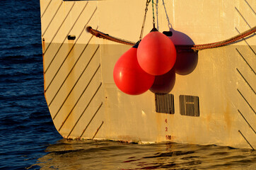 fishing boat in harbor with red buoys hanging from the back with depth level marking