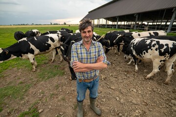 A mature male farmer is smiling in camera proud with his work on a countryside farm with...