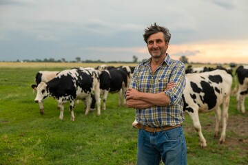 A mature male farmer is smiling in camera proud with his work on a countryside farm with...