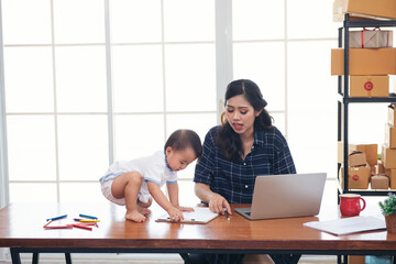 working asian mother baby kid and laptop computer at home office. freelance and motherhood work at anywhere concept. 