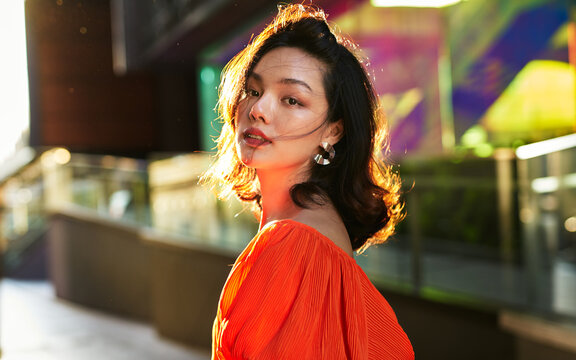 A beautiful Asian woman standing outside a shopping mall during sunset hour. The model has the looks for Japanese, Chinese, Thai or Taiwanese people.