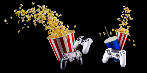 Flying popcorn, cup of soft drink and video game joystick isolated on black