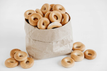 Drying or round bagels in a paper bag on a white wooden background. Copy, empty space for text