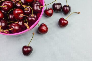 Fototapeta na wymiar Red organic ripe cherries on a pink bowl and on a light blue background