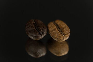 Two roasted coffee beans in a row, horizontal. Extreme close up, macro photography, selective focus. Background deep red, foreground textured black with light effects. Space for copy or text.