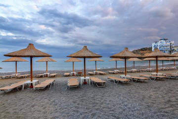 Desert beach with straw umbrellas waiting for tourists after quarantine. Fantastic white sand and sea. Beautiful summertime view seascape. Relax places island Crete, Greece. Free space for text.