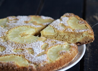 Sponge cake with pineapple on a dark wooden table.Home cooking.