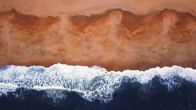 Flying over a sandy beach. Waves break on a sandy beach on the Atlantic coast, aerial View. Nazare, Portugal.