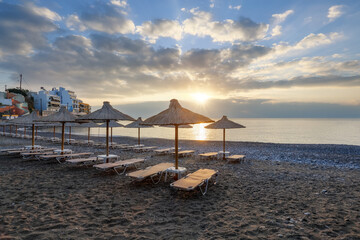 Empty beach with umbrellas and deck chairs closed. Unbelievable sunrise. Beautiful summertime view seascape. 2020 summer quarantine travel. Relax places island Crete, Greece. Free space for text.