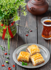 Turkish (eastern) dessert Ramadan Baklava with walnuts and hazelnuts, black strong Turkish tea in a glass of armudu (boomaly). Close-up, shallow depth of field, spring still life