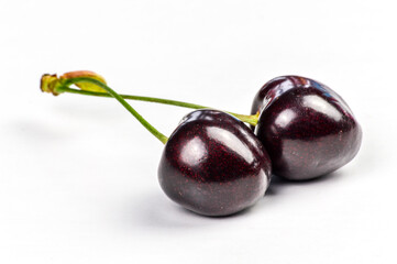 Couple of linked red organic ripe cherries on a white background close up