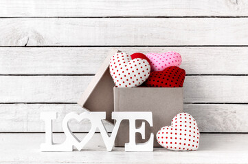 Obraz premium Many Red Heart Shaped with brown gift box and love alphabet over white wood background
