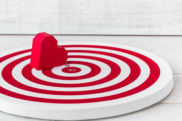 Fototapeta na wymiar Red Heart Paper Shaped on Red dartboard over white wood background