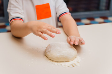 The child cooks. Hands concoct dough and flour. Kids' cooking class on baking