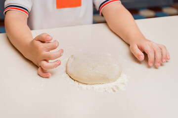 The child cooks. Hands concoct a cake from dough and flour. Kid's cooking class on baking