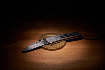 Silver jackknife on a wood table with a top light