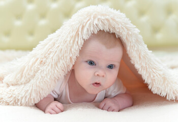 Fototapeta na wymiar Cute little baby girl playing under the blanket