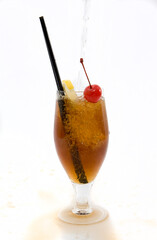 Tonic water pouring into a Cuba LibreRum cocktail, spilling over the glass on white background.
