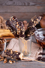 Chocolate Covered Bananas on a Stick in a glass beaker on wooden rustic table