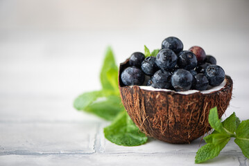 ripe blueberries with mint leaves in coconut shell