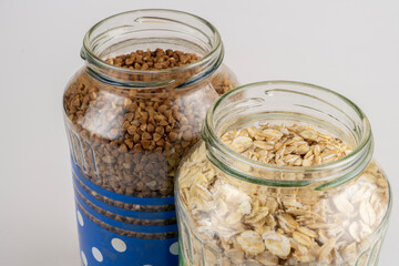 Buckwheat oat and rice groats in glass jars close-up on a background