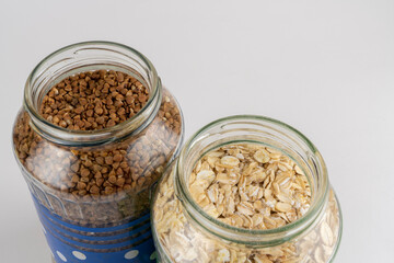 Buckwheat oat and rice groats in glass jars close-up on a background