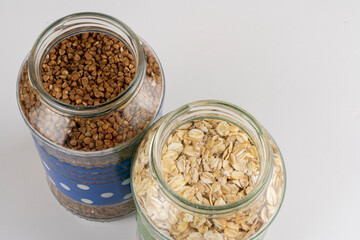 Buckwheat oat and rice groats in glass jars close-up on a background