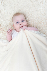 Cute little baby girl lying under the blanket
