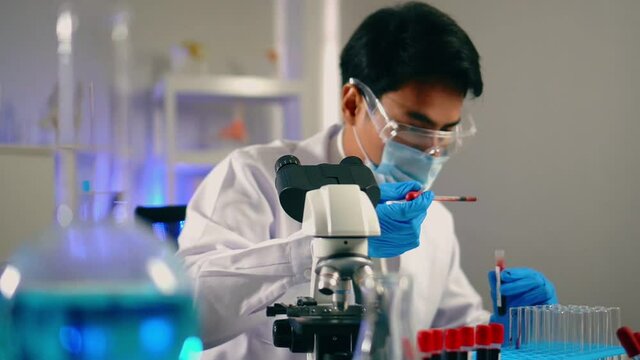 Slow motion, Young man scientist drop biochemical blood into test tube   for research and test in laboratory. Doctor and scientist work in laboratory pandemic of corona virus, COVID19 concept