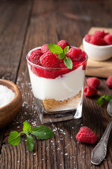 No bake cheesecake dessert in a glass jar topped with raspberry puree and fresh berries