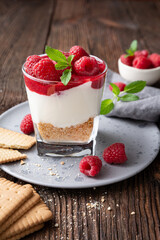No bake cheesecake dessert in a glass jar topped with raspberry puree and fresh berries
