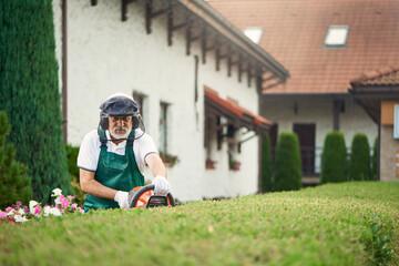 Man wearing ear and face protection cutting bushes.