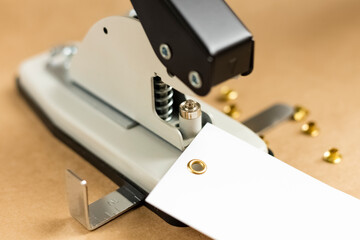 Tool or manual machine for installing the eyelet. Puncher and grommet installer on a wooden table