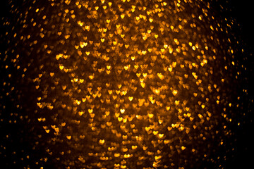 Dark background with golden bokeh in the shape of a heart. Valentine's day concept.