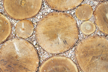 Round-shaped woods made of sawn wood are laid as a decorative coating along with small pebbles.