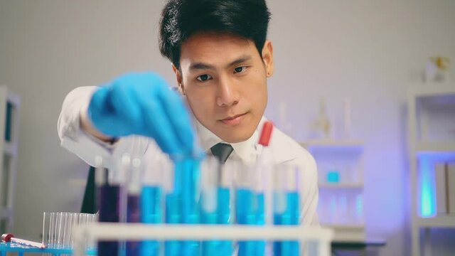 Slow Motion, Young Asian Handsome Man Scientist Looking Test Tubes And Smell Test Biochemical Liquid In Laboratory. Doctor And Scientist Work In Laboratory Pandemic Of Corona Virus, COVID19 Concept