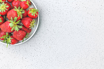 Fresh ripe organic strawberries in a white bowl. Juicy red delicious berries on a gray background. Space for text. Healthy eating concept