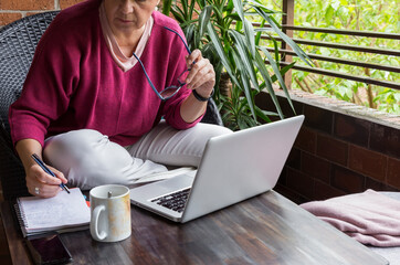 Woman with laptop working on the terrace at home