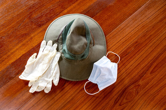 Photo of a hat with gloves and a surgical mask on a wooden table background