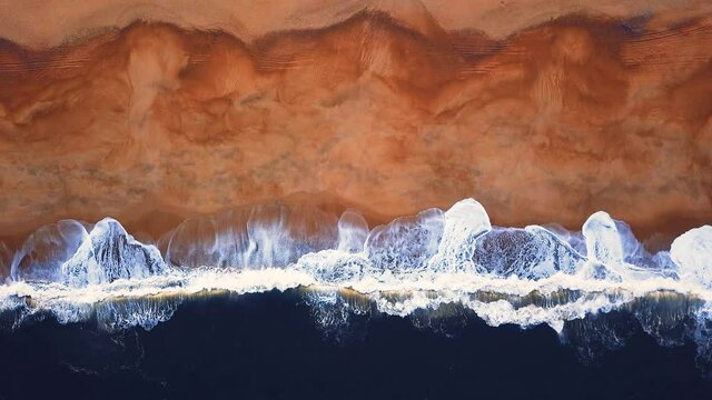 Flying over a sandy beach. Waves break on a sandy beach on the Atlantic coast, aerial View. Nazare, Portugal.