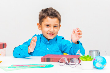 cheerful preschooler boy sitting at the table with a book.