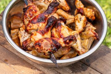 Appetizing grilled chicken legs and wings in a bowl. Close-up.
